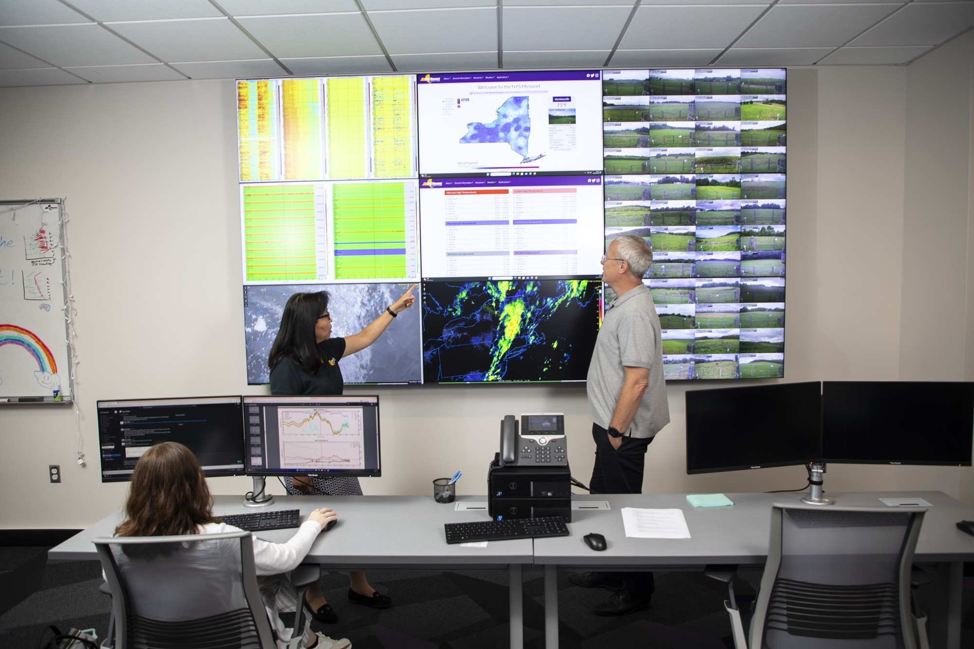 June Wang and Chris Thorncroft point at Mesonet data from the operations center.